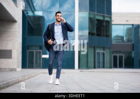 Young middle-eastern entrepreneur going home, talking on phone Stock Photo