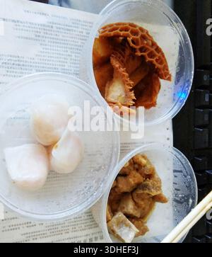 Three plastic containers of Chinese street food on a desk with chopsticks Stock Photo