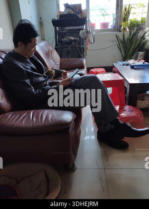 Man sitting on leather sofa using tablet in living room Stock Photo