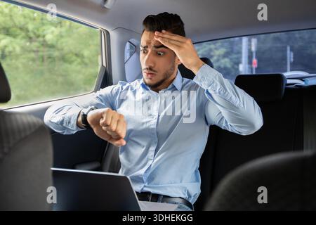 Worried arab businessman looking at watch while sitting in car Stock Photo