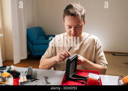 Young man repairing and inspecting all-in-one pc liquid cooler at home, servicing radiator, pump and tubing to maintain performance and upgrade Stock Photo