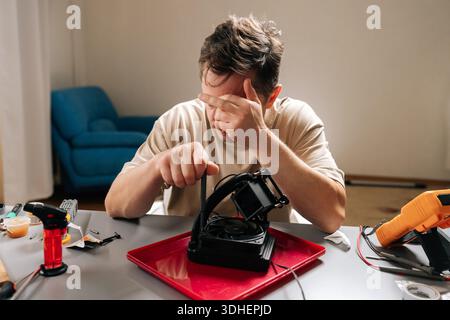 Man struggling with complex computer cooling system repair, feeling frustrated and stressed while troubleshooting difficult technology and hardware Stock Photo