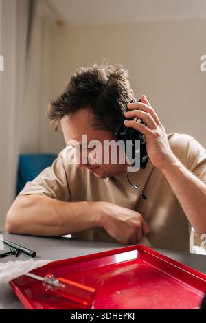 Man repairing computer cooling system, holding components, demonstrating expertise and focus fixing hardware issues at home office. Concept of Stock Photo