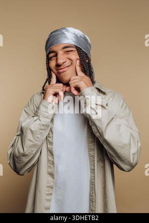 Young man with braided hair and bandana smiling playfully. Stock Photo