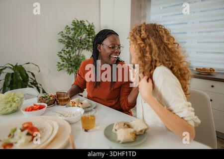 Diverse female friends enjoying lunch and laughing together Stock Photo