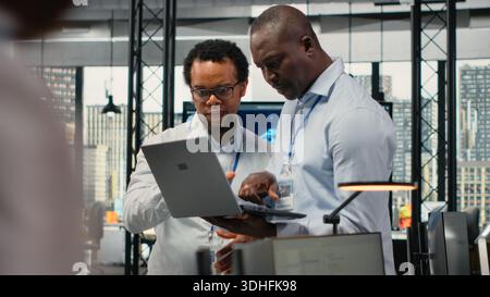 Team of technicians in office doing software development to launch new features. Startup coworkers writing computer programs, doing code testing and quality assurance, camera B Stock Photo