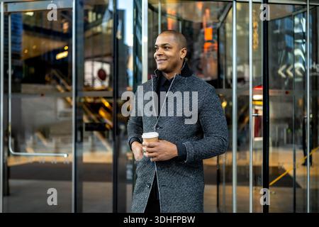 Confident businessman commuting holding coffee in city Stock Photo
