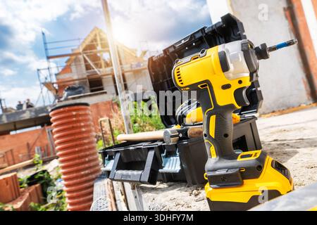 Tools are placed on a work surface near a building site with workers and construction in the background during daytime. Stock Photo