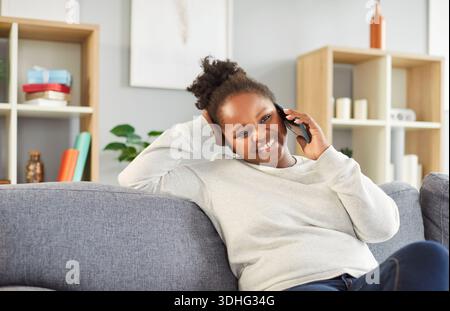 Happy African American Woman Talking On Smartphone During Leisure At Home Stock Photo