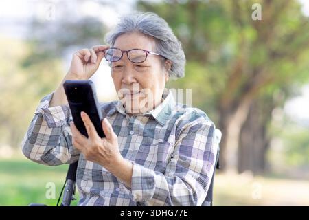 Poor Eyesight. Senior  woman Using Smartphone Wearing Eyeglasses Stock Photo
