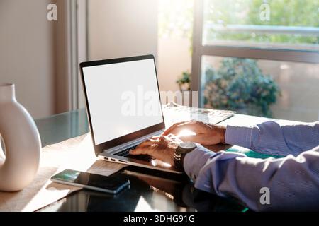 View of a business man hands using computer laptop. Blank white computer screen. Photo ready for mockup. Stock Photo