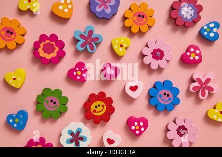 A vibrant flat lay of colourful beads flowers and hearts shape with cheerful patterns and smiley faces icon on soft pink background. Valentine's day Stock Photo
