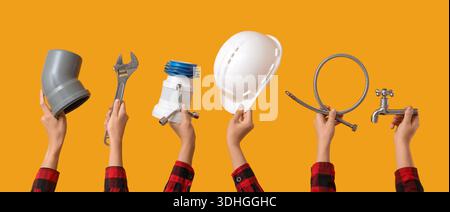 Hands with hardhat and plumber's tools on yellow background Stock Photo