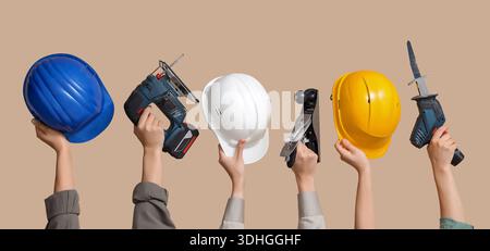 Hands with hardhats and construction tools on beige background Stock Photo