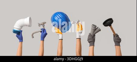 Hands with hardhat and plumber's tools on grey background Stock Photo