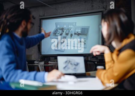Young Caucasian Man and Young Woman Discussing Architectural Floor Plan Stock Photo