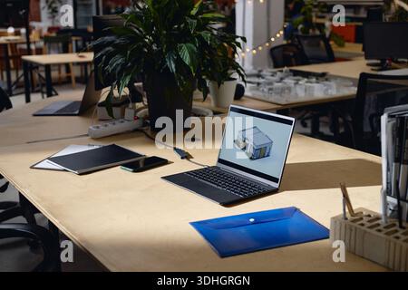 Modern Office Workspace Featuring Laptop Displaying Architectural Rendering Stock Photo