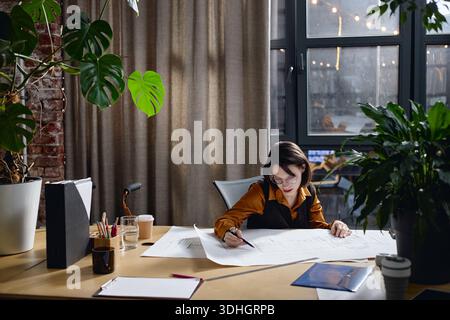 Young Adult Caucasian Woman Working on Architectural Blueprints in Office Stock Photo