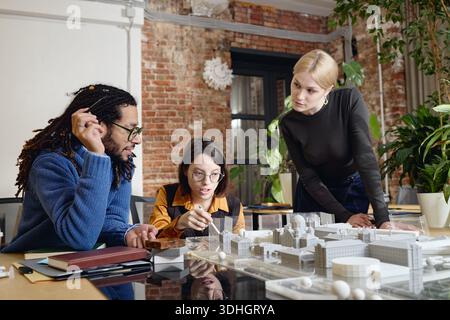 Multiethnic Young Adults Collaborating on Architectural Model in Office Stock Photo