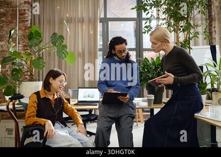 Multiethnic Young Adults Collaborating on Project in Modern Office Setting Stock Photo
