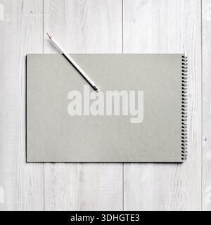 Blank notebook and pencil on light wooden surface. Branding template. Flat lay. Stock Photo