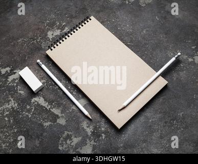 Closed blank kraft notebook, pencils and eraser on concrete surface. Stationery template. Stock Photo