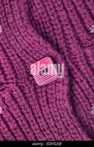Squred plastic button sewn on purple knit wool cardigan closeup Stock Photo