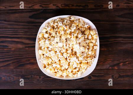 Popcorn in white bowl on dark wooden surface Stock Photo
