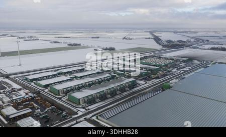Aerial view of a sprawling datacenter complex nestled amidst snow-dusted fields under a gray sky, a stark contrast of industry and nature, Middenmeer, Stock Photo