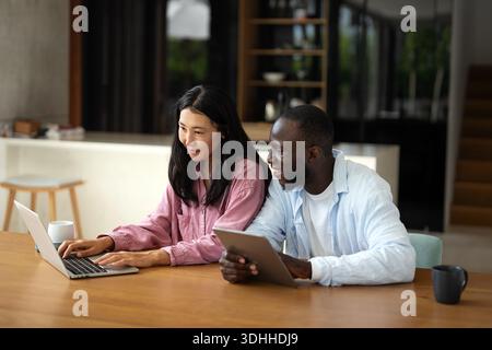 Business team, two happy diverse, multiethnic executives working together using laptop in office. Stock Photo