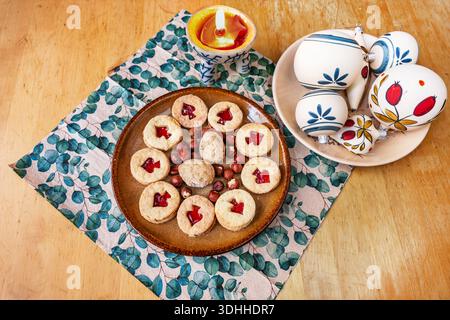 Many Linzer cookie and nut on plate, napkin, Christmas ball and candle lit on wooden table. Stock Photo