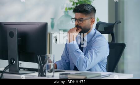 Indian businessman Arabian business man ethnic male worker guy professional entrepreneur working in office typing computer thinking ponder think idea Stock Photo