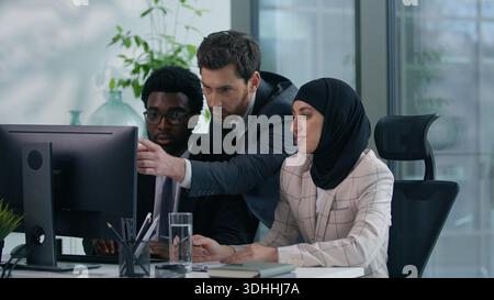 Multicultural business colleagues collaborating in modern office multiracial co-workers working African American male woman in hijab and Caucasian man Stock Photo