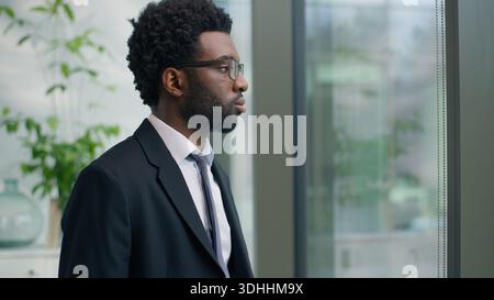 Creative thoughtful African American man business male entrepreneur businessman thinking idea startup corporate solution serious look at window in Stock Photo