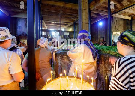 Believers light candles and pray inside the historic Orthodox church with stone walls and wooden structures Stock Photo