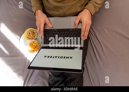 Bar, Montenegro, 22 January 2026, Man watching movie on Amediatheka platform site on laptop while sitting on bed at home Stock Photo