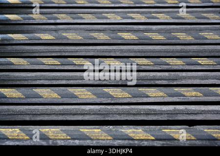 Worn yellow and black hazard warning stripes on old steps for use as a background Stock Photo