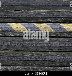 Worn yellow and black hazard warning stripes on old steps for use as a background Stock Photo