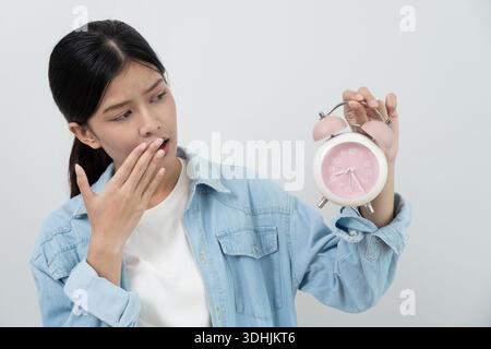 Shocked Asia young woman looking at clock alarm, lady is late appointment or work or class study, overslept, difficulty get up in mornings, time worri Stock Photo