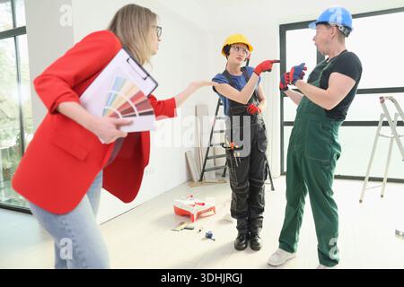 Team of skilled workers collaborating on a home renovation project in a modern living space Stock Photo