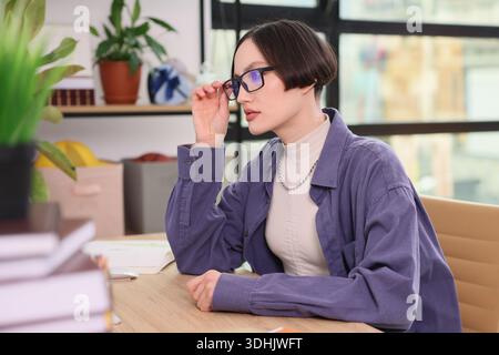 Engaging work session in a bright, modern office featuring a thoughtful young professional Stock Photo