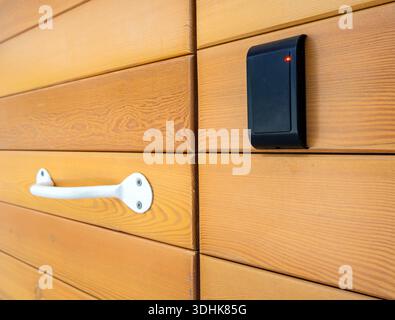 Fragment of a wooden door with a wireless access control reader Stock Photo