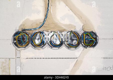 Boxes with cables for electric sockets installed in new house building empty wall Stock Photo