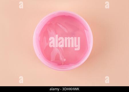 Pink jar of transparent cosmetic gel on beige background, closeup. Cosmetology and beauty concept Stock Photo