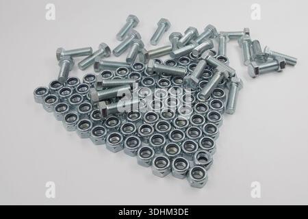 Metal hex bolts and nuts scattered on white background industrial fasteners set Stock Photo