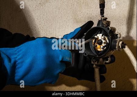 Close-up of electrician unscrewing electrical wire connection inside junction box using a screwdriver. Concept of electrical maintenance, repair work Stock Photo