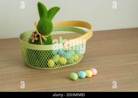 Easter basket with bunny and colored eggs on a wooden table. Stock Photo