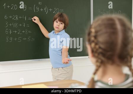 Schoolboy doing math on chalkboard in classroom Stock Photo