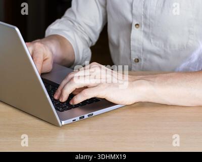 Hand engaging keyboard, notebook displaying holographic finance symbols in low light. Stock Photo