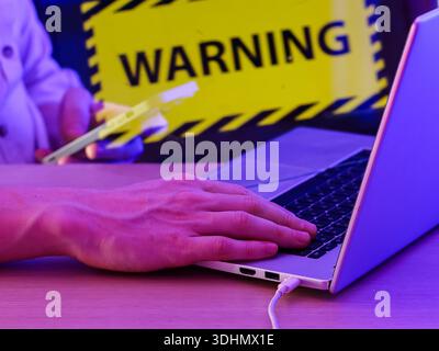 Close-up of hand on keyboard with digital warning symbol in background, illustrating cybersecurity threat. Stock Photo